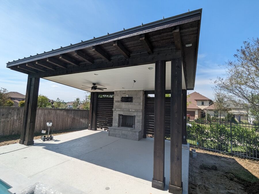 Freestanding patio pavilion with built-in slatted privacy wall screening and stone fireplace