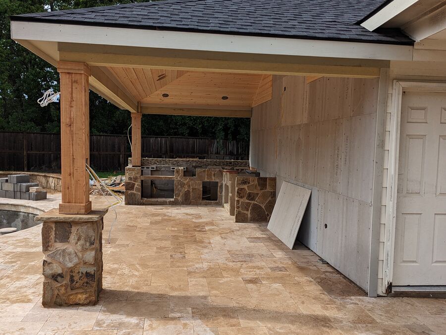 Patio cover with stone columns over travertine patio in Texas