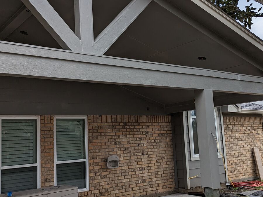 Gable patio cover with decorative trusses on brick home in Texas